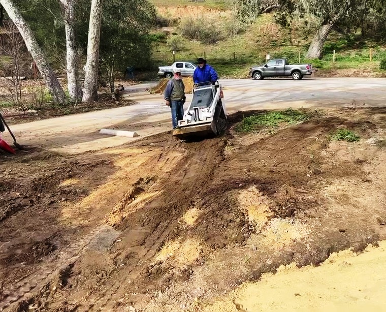 Bobcat loader shaping the path and bringing DG